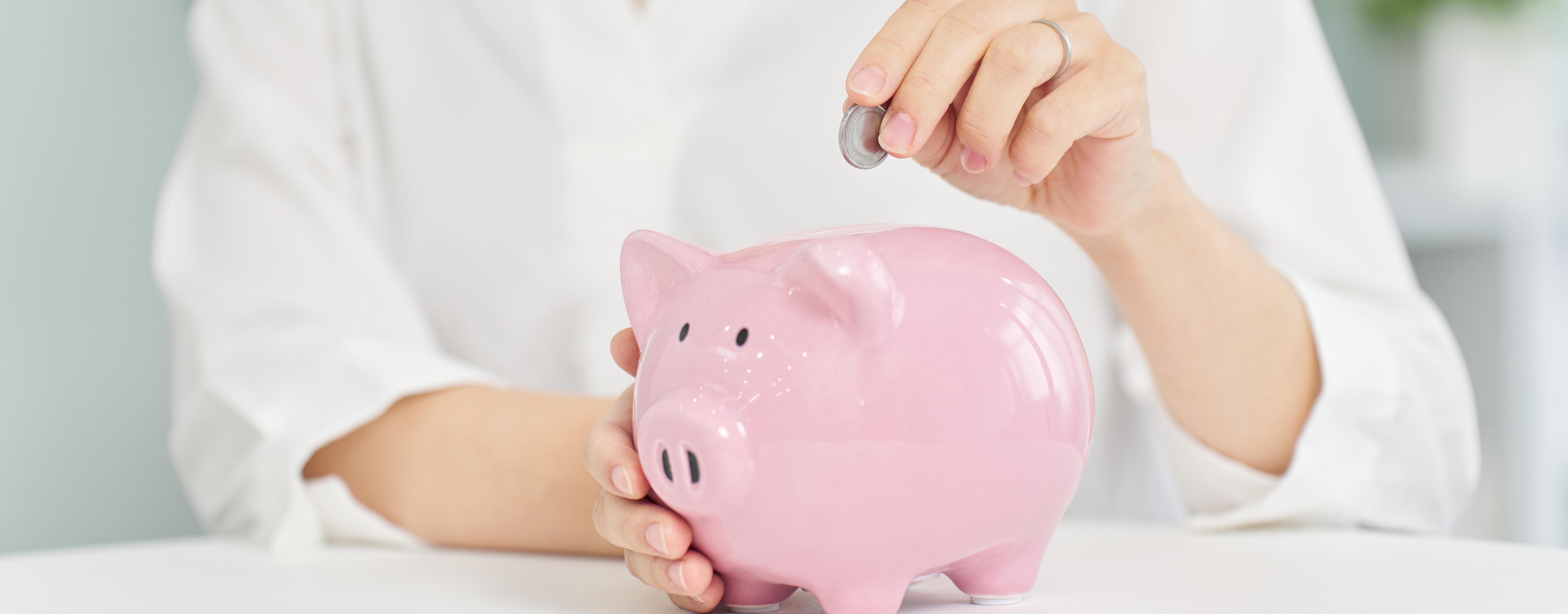 A woman putting money into a pig piggy bank